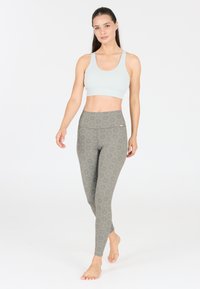 Lichtblauwe sportbeha met een ronde halslijn, gecombineerd met gemusterde, hoge taille leggings in grijze en beige tinten, met een bloemenpatroon.