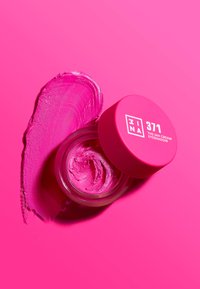 Ljust rosa krämögonskugga i en genomskinlig burk med matchande lock. Texturen är slät med en swatch av liknande nyans bredvid.