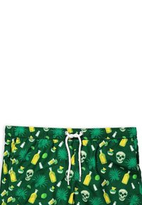 Pantaloni da bagno verdi con lacci bianchi. Il motivo presenta bottiglie gialle, lime, teschi e foglie tropicali. Tessuto dalla superficie liscia.