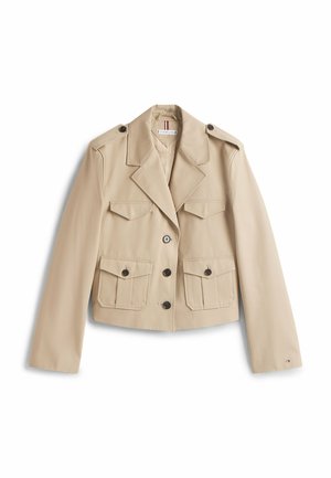 Beige cropped jas met twee voorzakken, reverskraag en knoopsluiting. Gemaakt van gladde stof, voorzien van vier knopen en schouderepauletten.