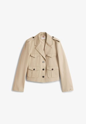 Beige cropped jas met twee voorzakken, reverskraag en knoopsluiting. Gemaakt van gladde stof, voorzien van vier knopen en schouderepauletten.