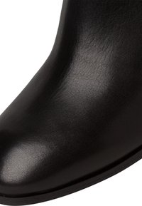 Czarne skórzane botki za kostkę o gładkiej fakturze, zaokrąglonym nosku i zaokrąglonym kształcie. Minimalistyczny design, bez widocznych elementów metalowych ani akcentów.