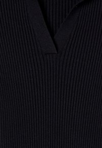 Top nero a coste con scollatura a V e tessuto testurizzato, caratterizzato da strisce verticali. Il design è aderente e leggero.