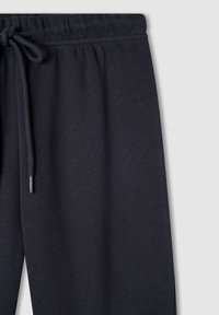 Ciemnoniebieskie spodnie dresowe wykonane z miękkiego materiału, z elastycznym paskiem w talii i sznurkiem do regulacji oraz luźnym krojem.