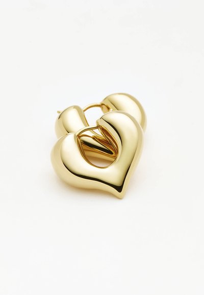 Σκουλαρίκια κρίκοι σε σχήμα καρδιάς με χρυσό τόνο, με λείες, γυαλιστερές επιφάνειες σε απλό λευκό φόντο.