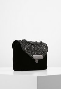 Borsa in velluto nero con parte superiore glitterata argentata, tracolla a catena e chiusura metallica con il nome del marchio "Valentino". Design compatto e strutturato.