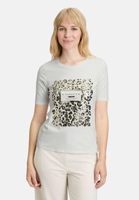 Lys grå kortærmet t-shirt med leopardprint-design og en rektangulær sort og hvid tekstlabel i midten.
