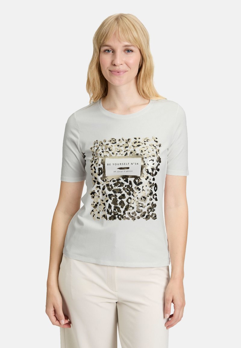 Lys grå kortærmet t-shirt med leopardprint-design og en rektangulær sort og hvid tekstlabel i midten.