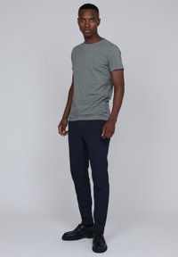 Camiseta gris de manga corta con cuello redondo, combinada con pantalones ajustados azul marino y zapatos negros con cordones. Diseño simple, sin patrones ni acentos.