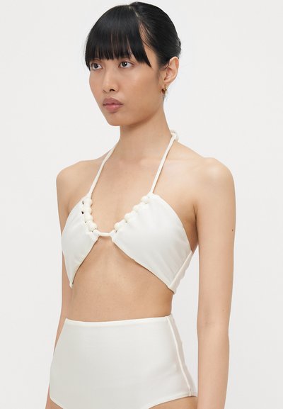 Costum de baie alb cu un design halter, prezentând cupe triunghiulare și accente decorative cu mărgele, asortat cu o parte de jos cu talie înaltă. Textură netedă.