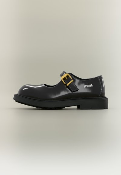 Chaussure Mary Jane en cuir verni noir avec une bride à boucle dorée et une semelle épaisse, avec le logo Moschino sur le côté.