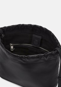 Schwarze Lederhandtasche mit einer weichen, gerafften oberen Kante, ausgestattet mit einer Innentasche mit Reißverschluss und glatter Textur. Minimalistisches Design, ohne sichtbare Logos.