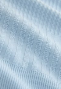 Țesătură tricotată bleu deschis cu dungi verticale alterante, unele zimțate, altele netede, pliată ușor.