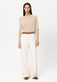 Beige knitted short-sleeve sweater, wide white trousers, brown belt with metal accents, and brown suede shoes. Simple, relaxed fit.