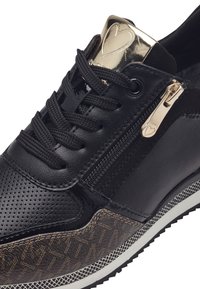Sneaker nera con tomaia in pelle perforata, dettagli lucidi, zip in metallo e suola intermedia marrone con motivo. Presenta lacci neri.