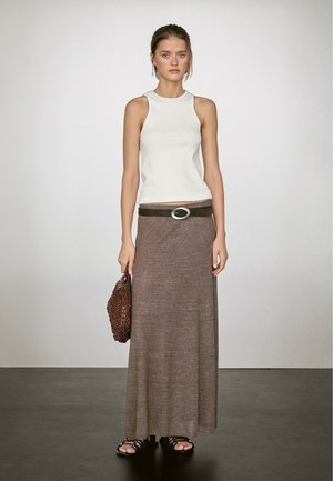 White sleeveless top, brown maxi skirt with a belt featuring a circular buckle, and a textured brown bag. Footwear is black strappy sandals.