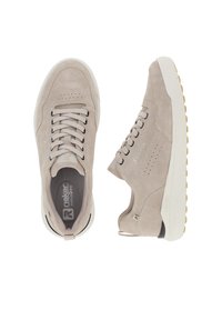 Beige suede sneakers with a textured finish, white rubber sole, and contrasting black laces. Notable perforations on side panels.