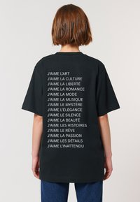 T-shirt noir en coton avec un texte blanc au dos énumérant des phrases commençant par "J'aime," dans une coupe décontractée avec des manches courtes.
