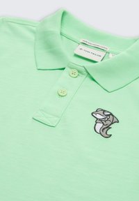 Lichtgroen polo shirt gemaakt van biologisch katoen, met een drievoudige knopenlijst en een geborduurd vissymbool op de linkerborst.