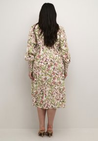 Florale maxi-jurk in lichtroze met groene en paarse accenten. Heeft pofmouwen en een losse pasvorm, reikt tot halverwege de kuit.