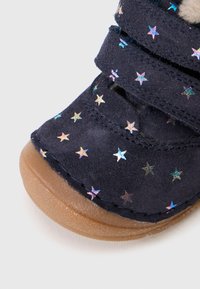 Marineblauwe suède schoenen met stervormige holografische accenten, voorzien van een rubberen zool en klittenbandsluitingen voor een verstelbare pasvorm.