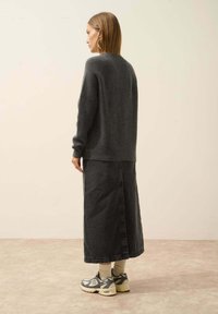 Harmaa pitkähihaisen neuleen yhdistelmä mustan farkkuhameen kanssa. Käytetään harmaiden tennareiden ja beigien sukkien kanssa; minimalistinen muotoilu, pehmeä rakenne.