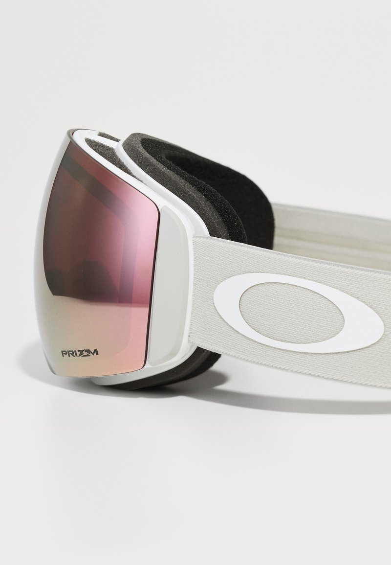 Weiße Skibrille mit einer leicht rosa Linse, grauem Plüschschaumstoffpolster und einem elastischen Band mit einem weißen Logo. Entwickelt für Leistung und Komfort.