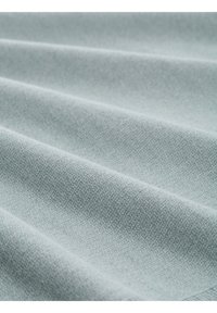 Tejido de color azul claro con una textura sutil y un patrón de tejido discreto, que muestra suaves pliegues y una superficie lisa. Adecuado para tapicería o uso en moda.