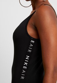 Svart linne i stretchigt material, med en diskret sidologotyp "AIR NIKE" i vitt. Designat med en diskret rundad halsringning och smala axelremmar.