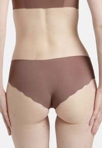 Bruna sömlösa boxershorts med vågig nederkant, tillverkade av slät tyg, med låg midja och minimalistisk design.