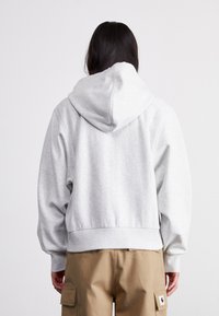 Grå hettegenser laget av myk stoff, med stor hette, drop-shoulder design og ribbet søm, kombinert med kaki cargo bukser.