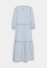 Vaaleansininen farkkuhaalari, jossa on kerroksellinen hameosa, pitkät hihat ja takana nappisuljenta. Sisältää rypytetyn vyötärön ja käännettävät hihat.