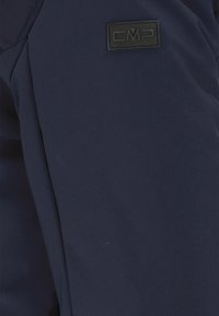 Mørkeblå stof med en glat tekstur; har en sort rektangulær CMP-logo patch på den øverste del af armen.
