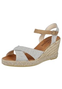 Sandalias de cuña con base de yute trenzado, tiras cruzadas plateadas y correa para el tobillo en color marrón. Parte superior de tela texturizada con plantilla acolchada.