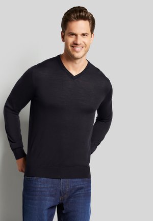 Schwarzer V-Ausschnitt-Pullover mit langen Ärmeln, aus leichtem Stoff gefertigt. Verfügt über gerippte Bündchen und Saum, kombiniert mit blauen Jeans.