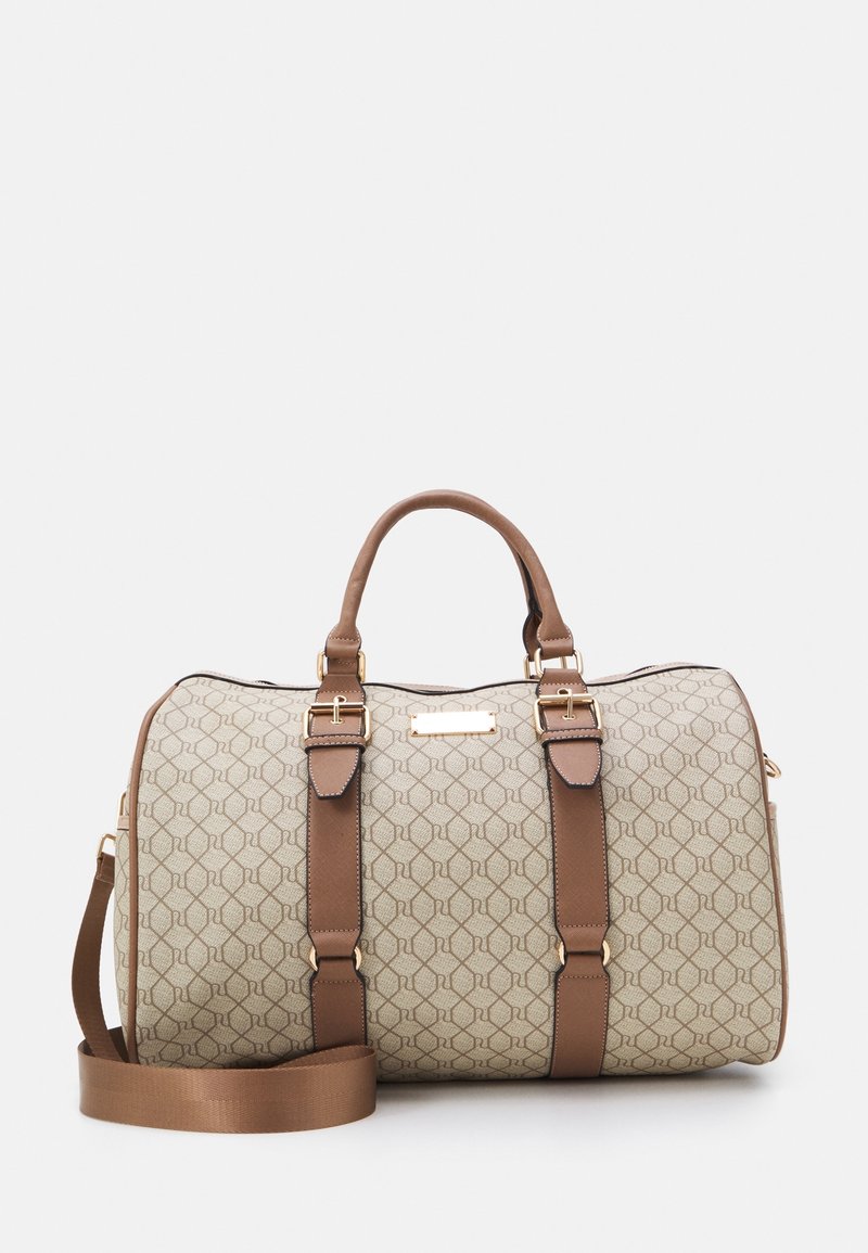Sac de voyage beige et marron à motifs, avec deux anses, une bandoulière réglable et des accents de boucle dorée sur fond blanc.