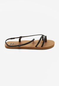Schwarze geflochtene Riemen an einer beigen flachen Sandale mit strukturiertem Sohlen. Ohne Verschluss, mit einem minimalistischen Design, das sich für die Freizeit eignet.