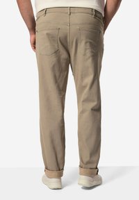 Vaaleat beige-housut, joissa on kaksi takataskua, rento malli, käärityt lahkeet, valmistettu pehmeästä kankaasta, yhdistetty valkoisiin tennareihin.