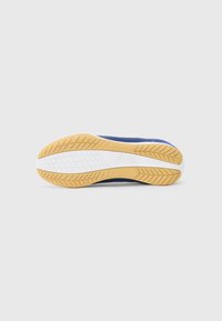 Sneaker sole with a patterned rubber outsole in tan, white midsole, and blue upper textile, featuring a smooth texture and curved design.