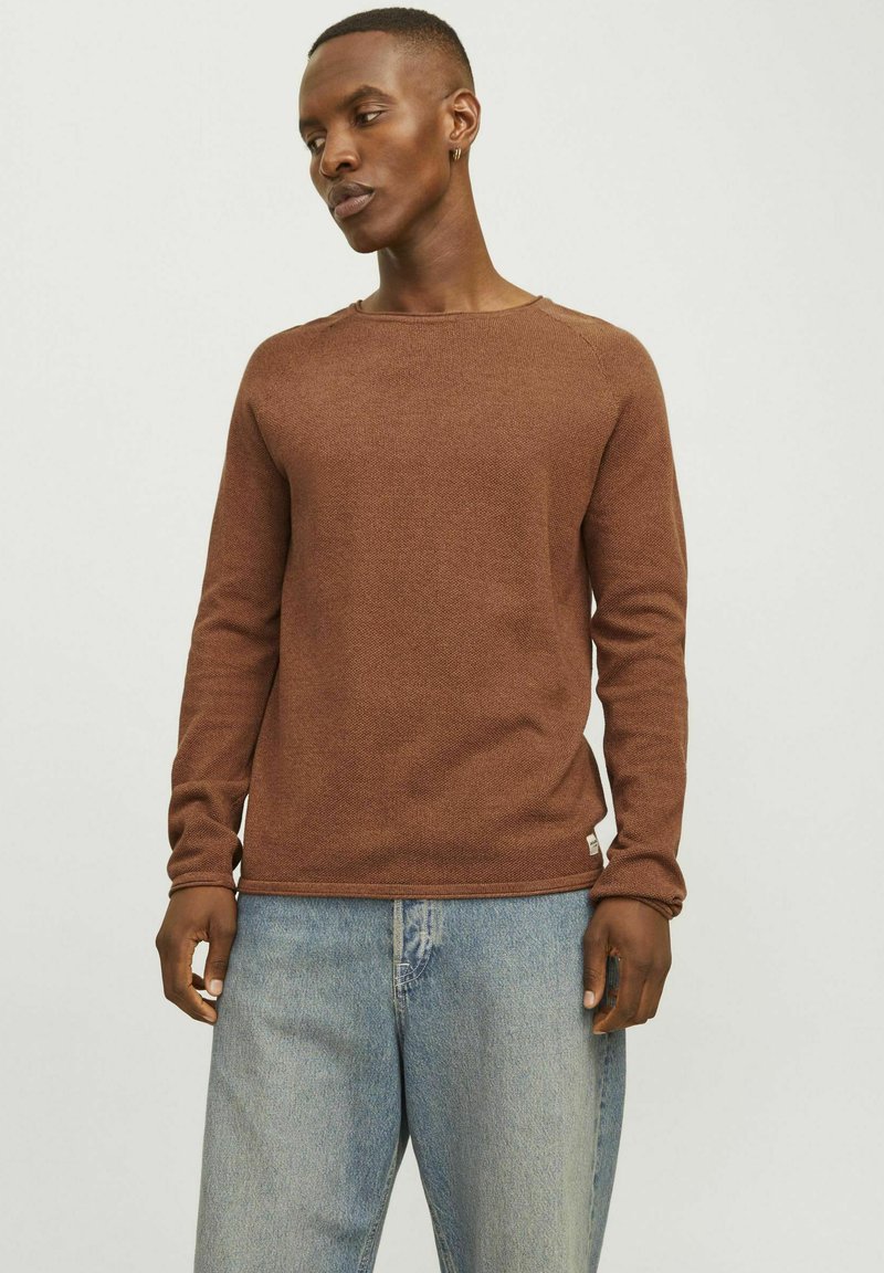 Bruine getextureerde langemouwen shirt met een ronde hals, nauwsluitend bij de polsen, gecombineerd met lichtblauwe spijkerbroek.