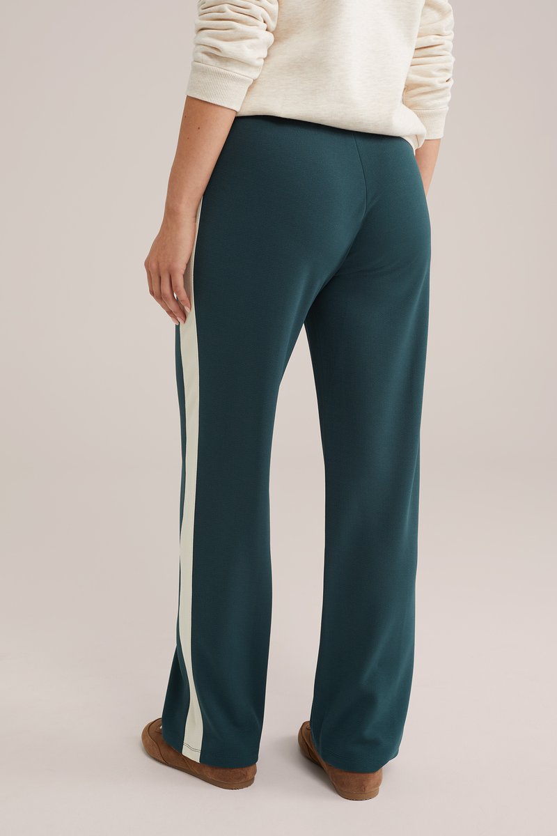 Zilas sporta bikses ar baltām sānu svītrām, mīksta auduma, ar izplešanos uz lejas un elastīgu jostasvietu. Raksturīgs gluds, teksturēts apdare.