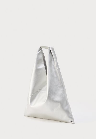 Ασημί μεταλλική τσάντα tote από μαλακό δέρμα με τρίγωνο σχήμα και μικρή λαβή στο πάνω μέρος, σε απλό φόντο.