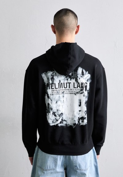Hoodie negro con un gran estampado gráfico blanco en la parte posterior, que presenta texto y diseños abstractos. Hecho de una tela suave con un ajuste relajado.