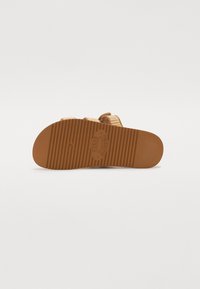 Pruun kummist põhi horisontaalsete soontega. Pehmed beežid kootud ülemised rihmad. Sildil "S Steve Madden" on reljeefne kiri kanna lähedal.