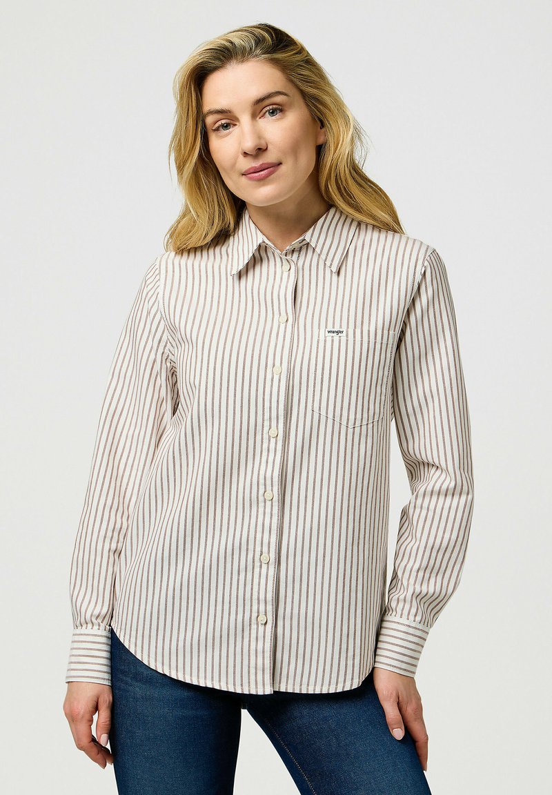 Camicia a righe di colore crema con sottili linee marroni e blu, dotata di una tasca sul petto e di un piccolo logo del brand sul lato sinistro.