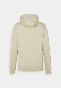 Sudadera beige con capucha ajustable mediante cordón, mangas largas y puños acanalados. Tejido suave, textura lisa y diseño minimalista.