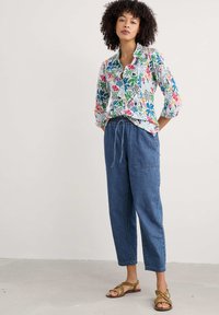Chemise florale à coupe décontractée avec des motifs multicolores ; en tissu léger. Associée à un pantalon en denim bleu avec une taille élastique.