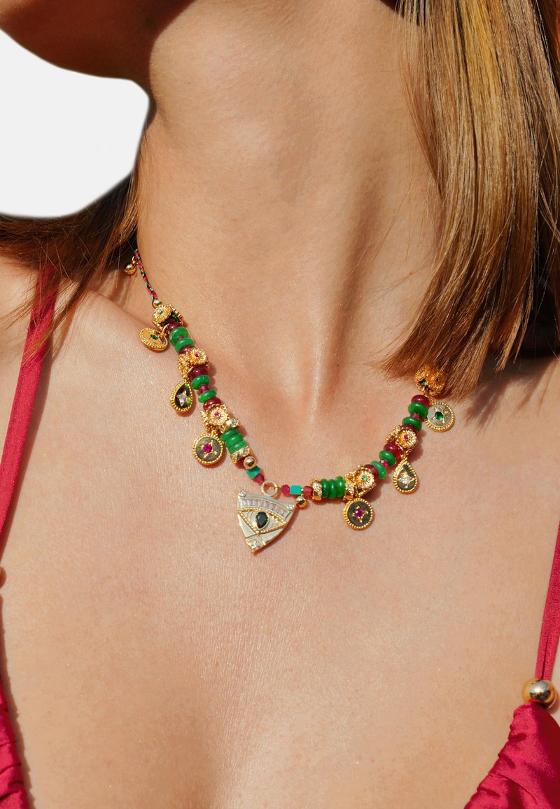 Collier en ton doré avec diverses perles, y compris vertes, rouges et éléments décoratifs. Comprend un pendentif triangulaire avec un motif d'œil.