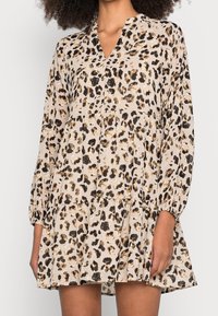 Leopardenmuster-Kleid in Beige, mit Puffärmeln, einem V-Ausschnitt und einem gestuften Rockdesign. Hergestellt aus leichtem, fließendem Stoff.