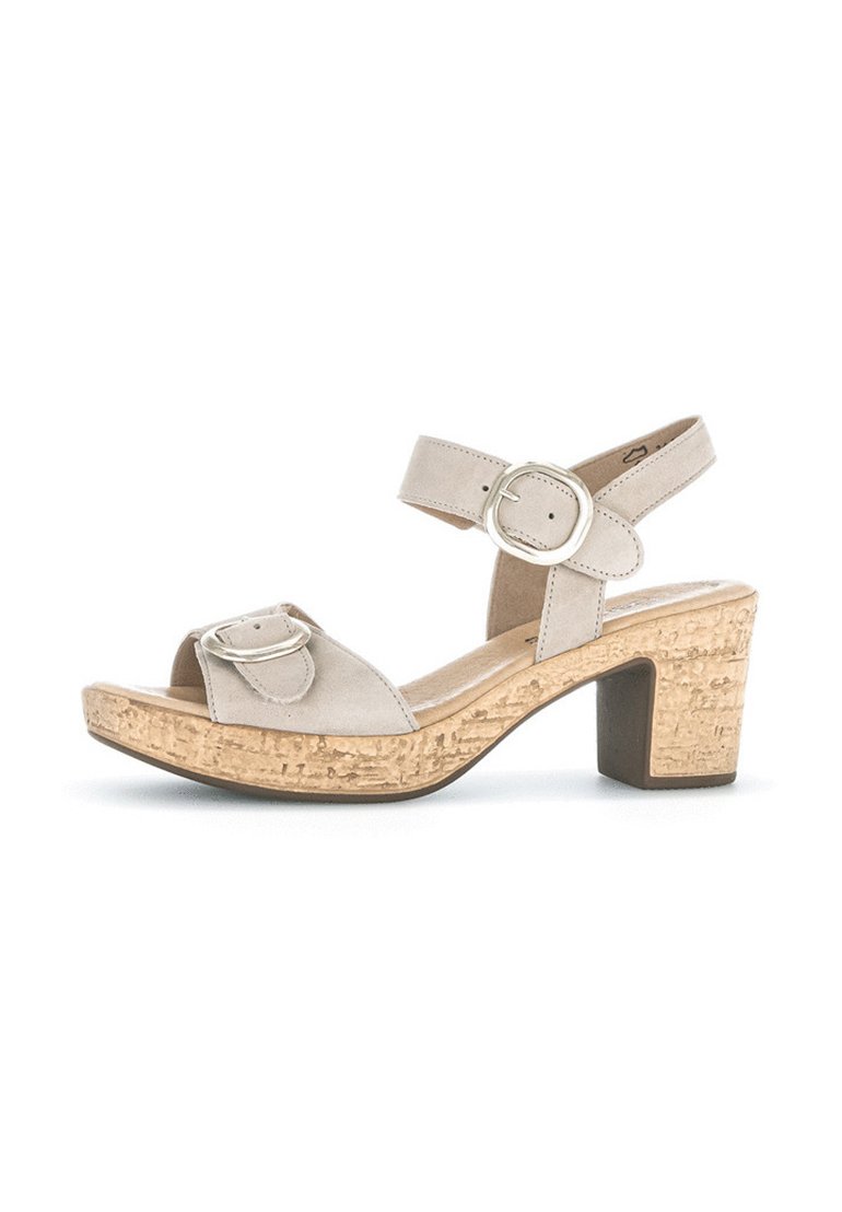 Beige suède hakken sandalen met een kurken middenzool, voorzien van een brede voorband, een verstelbare enkelriem en een zilveren gespdetail.